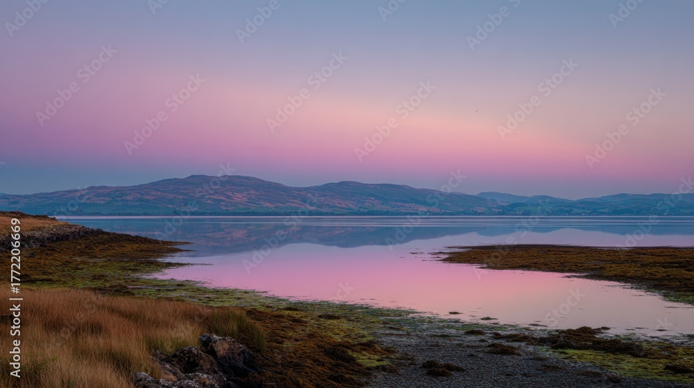 Obraz premium Tranquil Sunset Over Calm Water with Reflective Shoreline and Mountains in Twilight