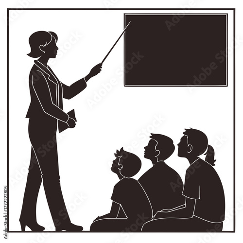 A teacher in a suit stands and points to a blank blackboard with a pointer while students sit on the floor and listen attentively to the lesson