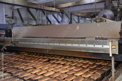Mass production of bread at factory conveyor belt with finished loaves