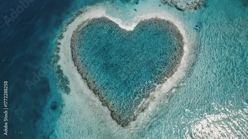 Aerial view of a heart-shaped reef in turquoise waters, surrounded by deep blue ocean