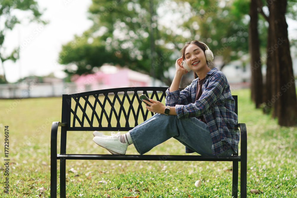 Fototapeta premium Smiling woman enjoying music outdoors in park