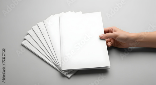 Brochure mockups in hand offering marketing collateral presentation and blank catalog design with copy space option