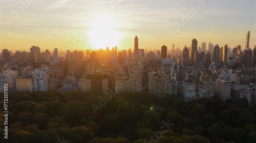 Breathtaking Drone shot over New York City Central Park at sunrise with colorful trees at full, morning light scene of cityscape, tall building stands agains the sun. New York, USA