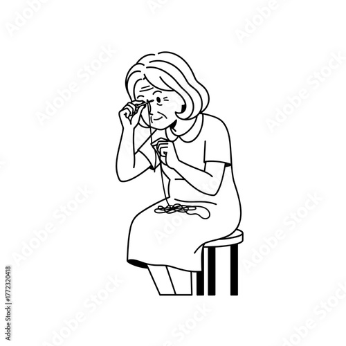 Older woman struggling to thread a needle while sitting on a stool  