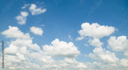 the sky is clear blue with fluffy white clouds, the sky is very bright, and the sun shines.