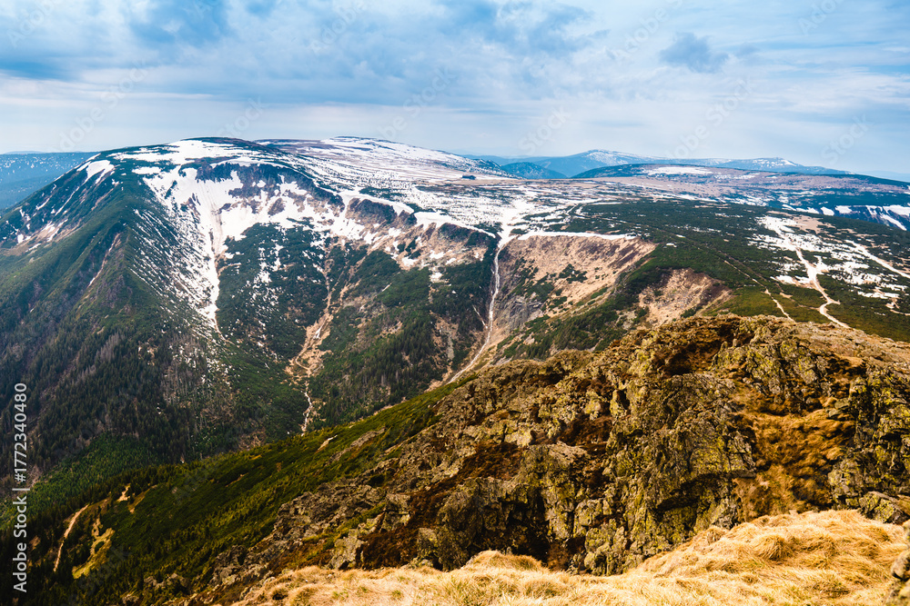 Fototapeta premium Snow-covered mountain ridges and rocky slopes of Krkonose National Park, Czech Republic, near Snezka peak, scenic panoramic view in springtime.