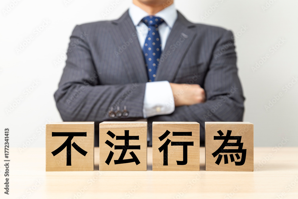 Obraz premium 「不法行為」と書かれたブロックと腕組みをするビジネスマン