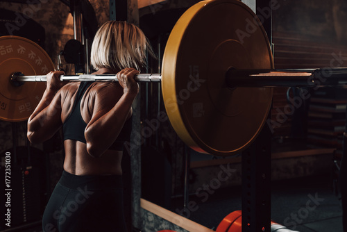 Caucasian fitness woman lifting a barbell in a gym, focused on strength training