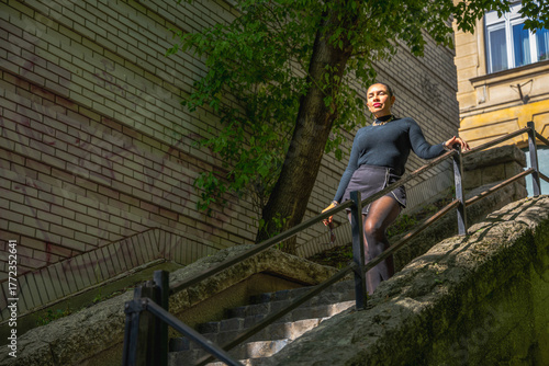 Wallpaper Mural Stylish woman descending an old stone staircase on a sunny day, surrounded by urban architecture and greenery, expressing confidence and elegance in motion. Torontodigital.ca