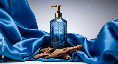 Elegant Blue Glass Pump Bottle with Gold Pump on Natural Wood and Silk