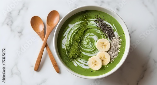 Minimalist green matcha smoothie bowl styled on a marble countertop with wooden utensils