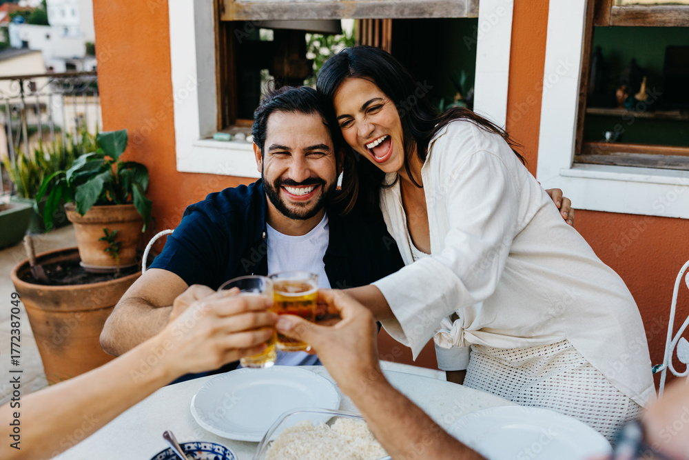 Obraz premium Happy couple celebrating with drinks at a cozy outdoor barbecue gathering