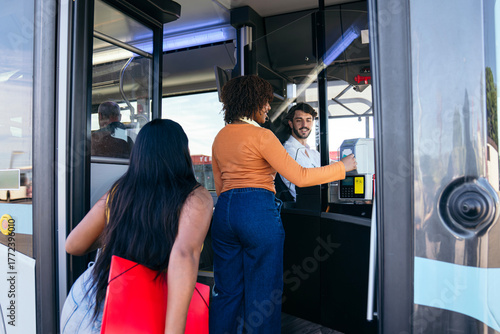 Foto Woman tapping card on payment terminal while boarding a public city bus, with ot
