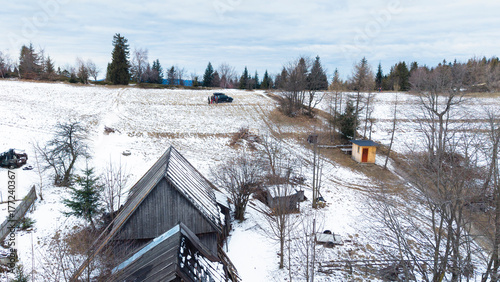 Картината върху платно A tranquil winter panorama of Beskid Mały in southern Poland, where snowy meadows meet evergreen forests and rolling mountain hills under a serene, cloud-streaked sky