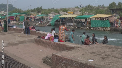 people taking a sacred dip in the narmada river at bhedaghat, with flowing waters, riverside stalls and temple visitors engaging in spiritual cleansing, jabalpur, india