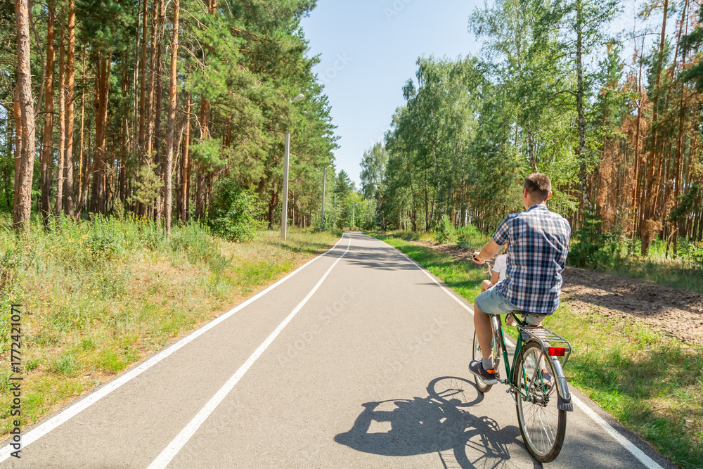 Obraz premium Young father with his little daughter on bicycle in summer sunny forest