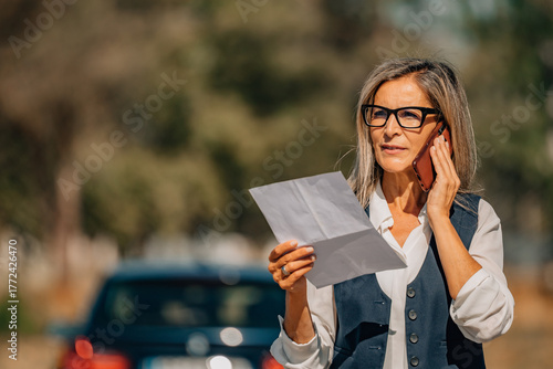 Wallpaper Mural insured female driver or client with vehicle talking on cell phone with document, insurance Torontodigital.ca