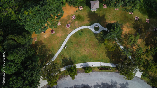 Top view aerial photo from flying drone of a city park with walking path and green zone trees in a sunny day.