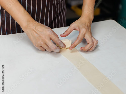 Close-up hand of asian young woman rolling dough into rolls with butter for homemade bread cooking on table in kitchen home, preparation ingredients desserts process making buns manually bakery baking