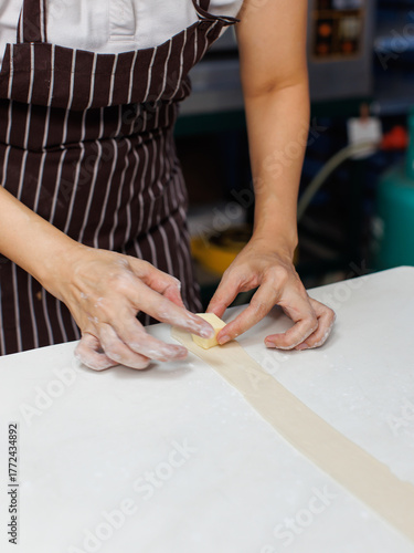 Close-up hand of asian young woman rolling dough into rolls with butter for homemade bread cooking on table in kitchen home, preparation ingredients desserts process making buns manually bakery baking