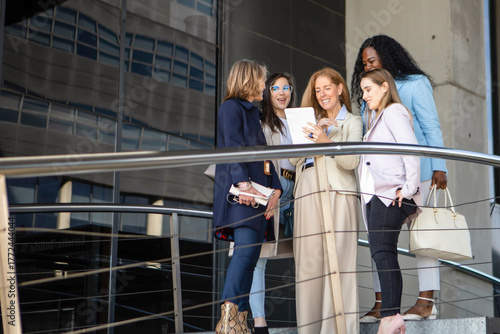 Group of professional women discussing plans at a modern building during the afternoon