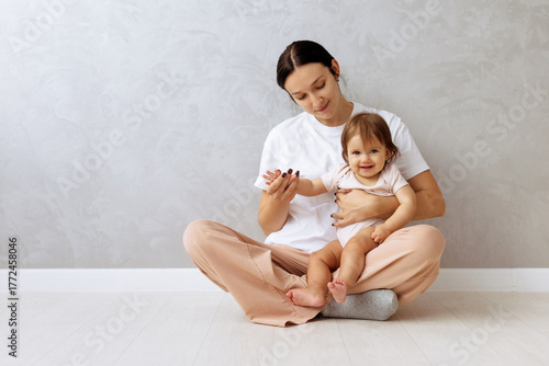 Konstfotografi Smiling baby sitting on mothers lap on floor and playing joyfully