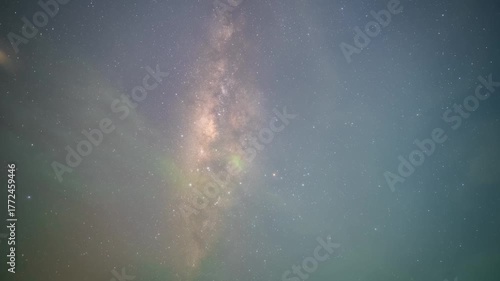 Timelapse of Milky Way across deep blue night sky with scattered clouds and glowing stars