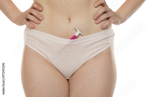 Studio shot of woman’s torso with pink razor tucked into underwear on white background.