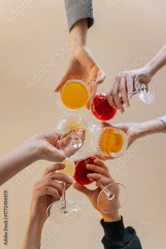 Bottom view of a group of friends making cheers with cocktails during a celebration in a restaurant. Friends relaxing at a bar with alcoholic drinks