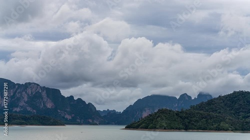 Sunset timelapse over Chiew Larn Lake with calm water, dramatic sky and surrounding mountain landscape