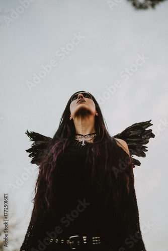 woman dressed and made up as a black angel with wings in the nature