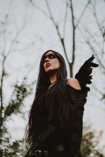 woman dressed and made up as a black angel with wings in the nature