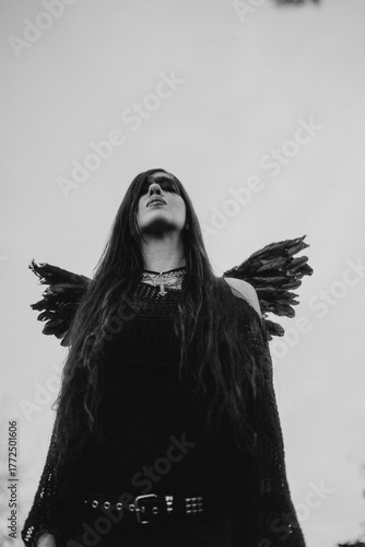 woman dressed and made up as a black angel with wings in the nature