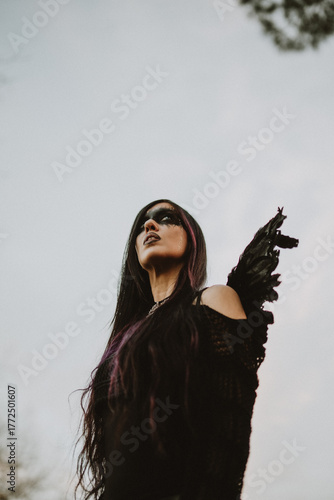 woman dressed and made up as a black angel with wings in the nature