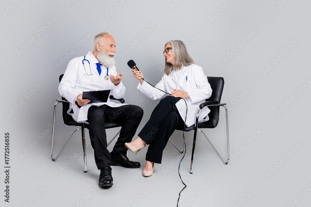 Obraz premium Two experienced doctors in white coats interview a senior physician during a medical consultation and checkup in a modern clinic style setting