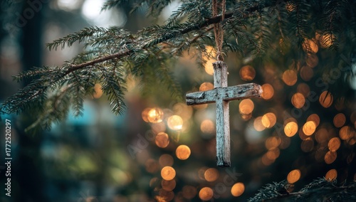 A christian cross hanging on a Christmas tree.