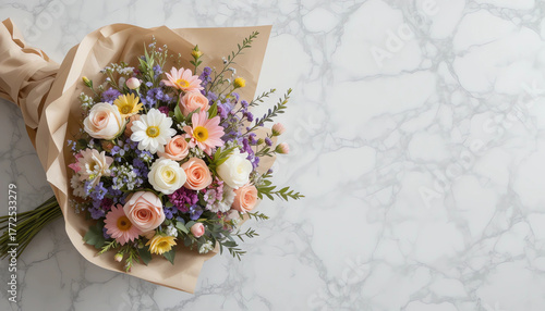 Top view of floral bouquet wrapped in paper, laid flat on marble table