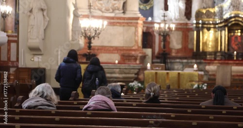 Worshippers sit scattered across wooden pews during a quiet service in a Baroque church; warm chandeliers and altar candles glow softly, evoking contemplation, faith, and calm.