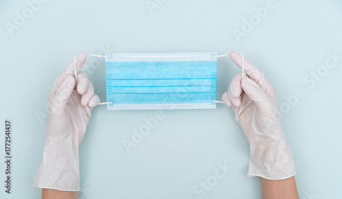 Hands wearing disposable gloves holding a mask