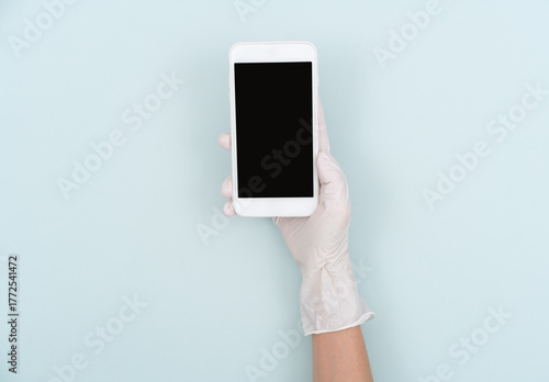 Holding a mobile phone with hands wearing disposable gloves