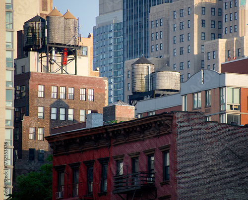 View of water towers perched atop aged brick buildings, a blend of old and new against the backdrop of modern skyscrapers, New York, New York, United States.