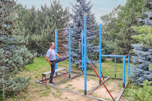 Active Senior Man Stretching on Outdoor Gymnastics Equipment in a Park