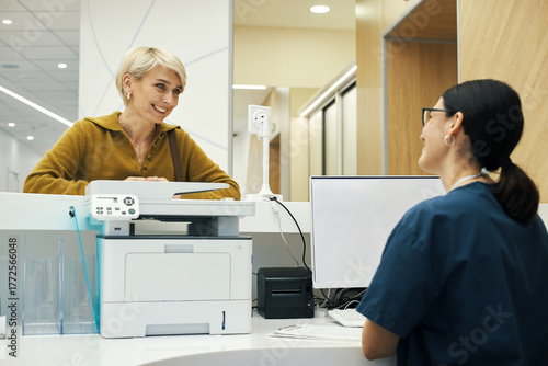 Foto Caucasian middle aged woman smiling and talking to young adult woman receptionis