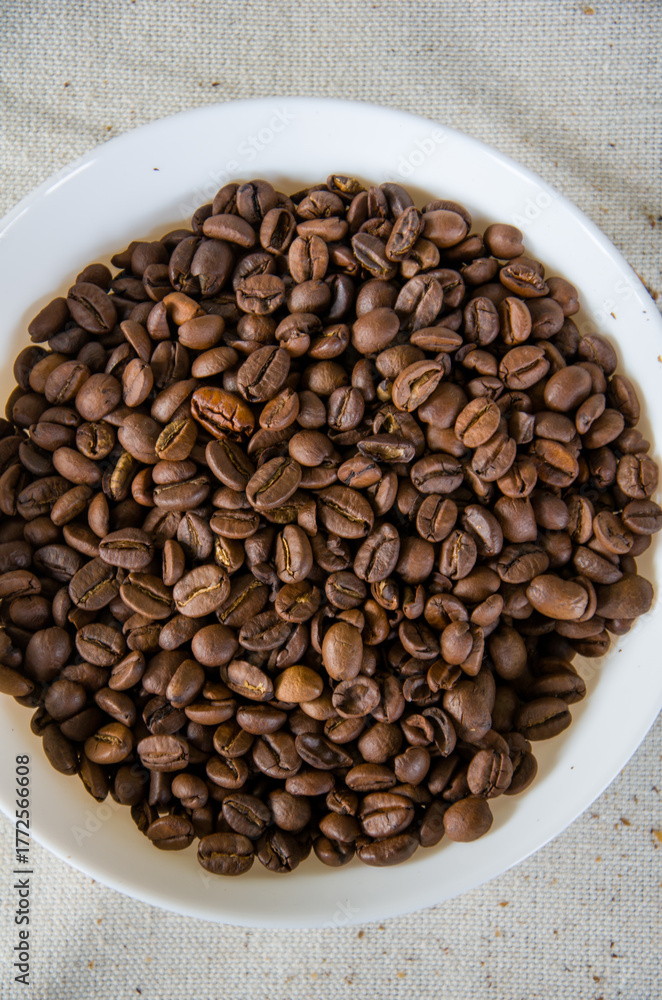 Fototapeta premium Abundance of Roasted Coffee Beans in White Bowl, Overhead View