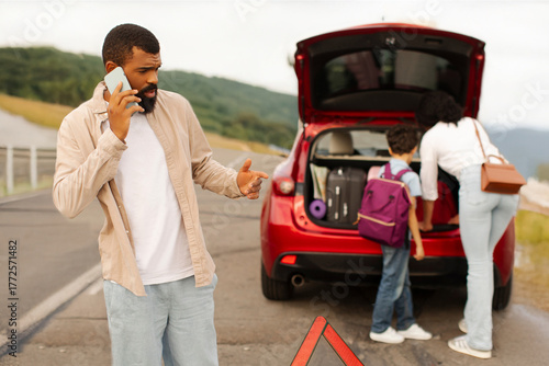 Fotografi Black family with child standing near broken down car on their way to vacation,