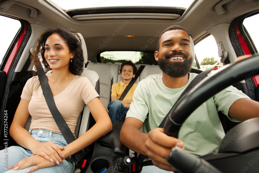 Obraz premium Road trip. Happy Black family of three riding car and smiling, traveling by automobile. Latin parents and son enjoying auto ride together