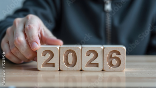 Wallpaper Mural Close-up hand flipping wooden cube changing year number from 2025 to 2026, symbolizing new year transition and fresh beginning. Torontodigital.ca