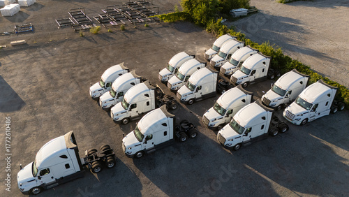 Foto Several white semi-trucks are parked in a lot.