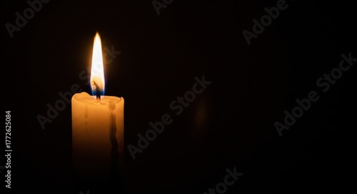 One burning candle flame at night closeup on a black background with copy space for text
