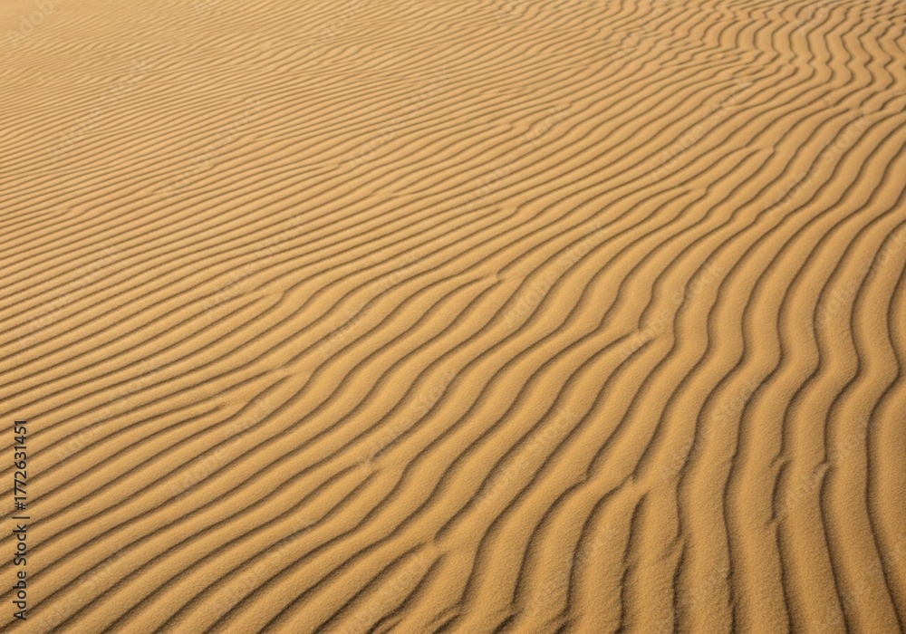 Fototapeta premium Golden sand dune texture with wavy ripples and diagonal lines for an abstract nature background